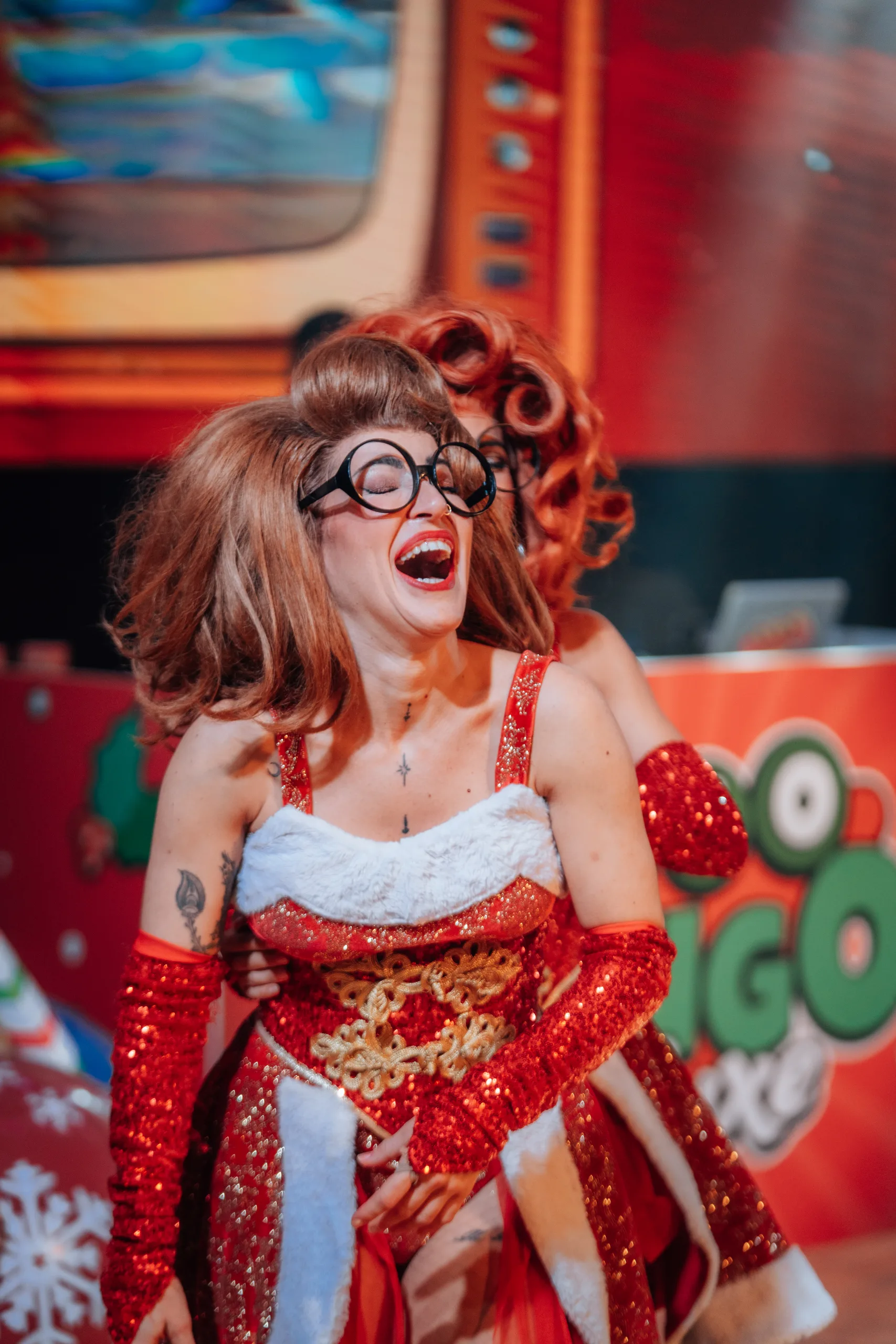 Azafata de Loco Bongo con gafas de pasta y vestido rojo de lentejuelas riendo en el escenario