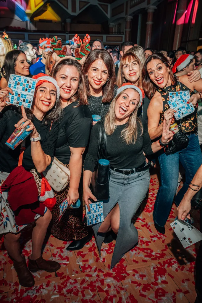 Grupo de amigas posando entre confeti en la fiesta Loco Bongo de Navidad